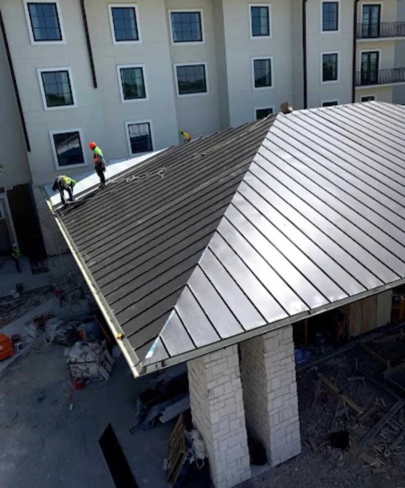 Crew installing standing seam metal roof panels on a commercial project in Springfield